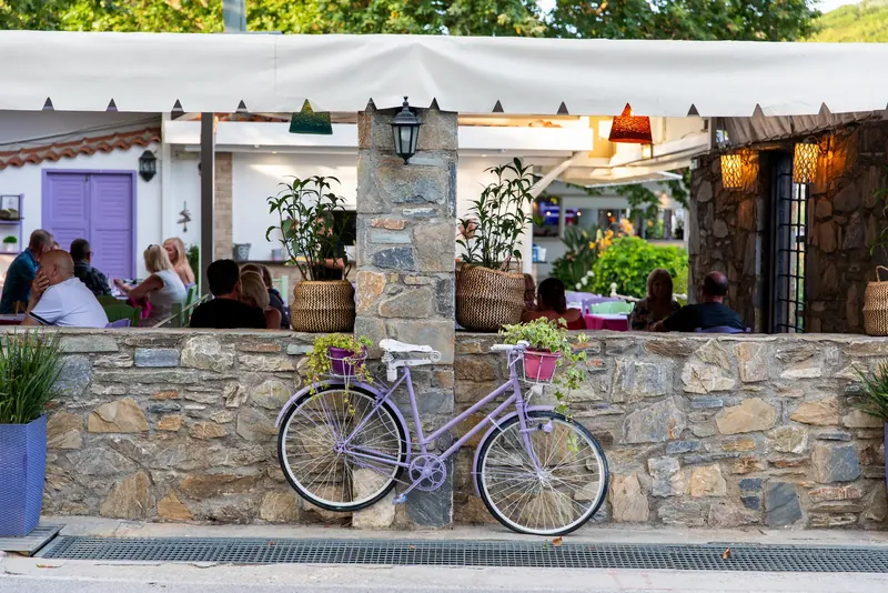 A stone wall with a lilac bicycle in front of the terrace