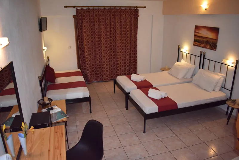 A twin room with a red curtain and a desk