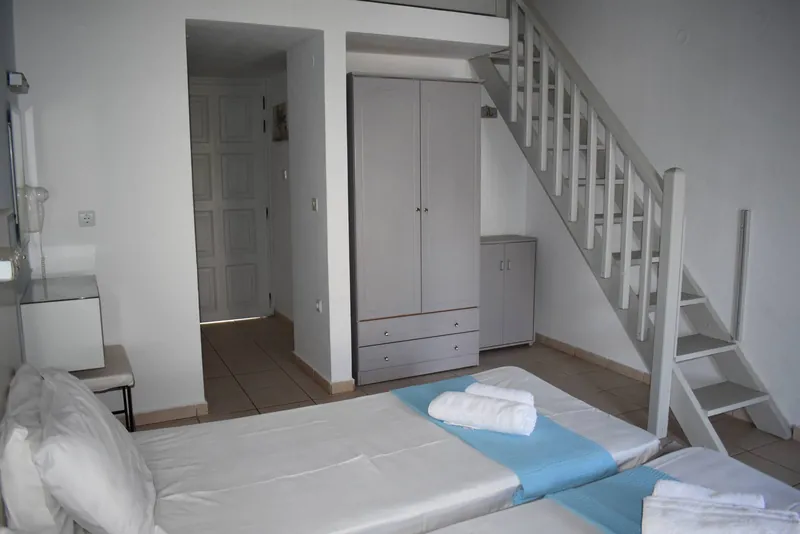 A room with a wooden staircase up to a loft