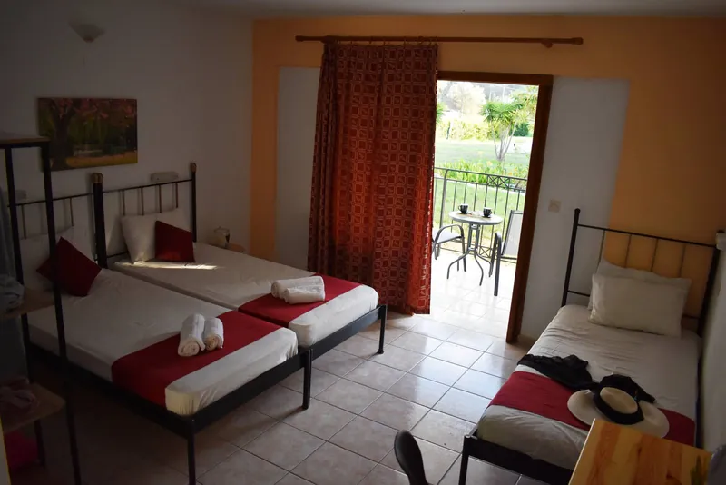A room with three beds and the balcony door open